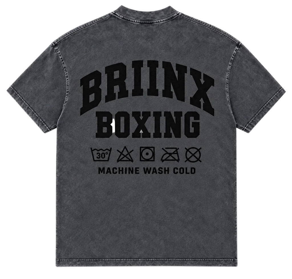 A dark gray acid-wash t-shirt shown from the back, featuring a large black graphic print that reads 'BRIINX BOXING' with laundry care symbols and 'MACHINE WASH COLD' underneath.