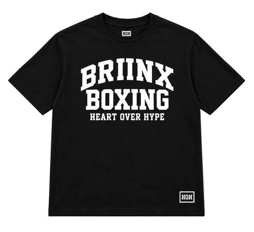A black short-sleeve t-shirt with a bold white graphic print on the front reading 'BRIINX BOXING HEART OVER HYPE', along with a small white 'ROH' logo on the bottom right hem and inside the collar, shown on a neutral gray background.