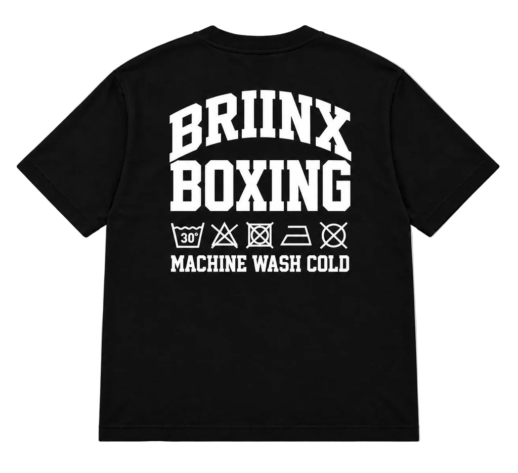 A black short-sleeve t-shirt shown from the back, featuring a bold white graphic print that reads 'BRIINX BOXING' with laundry care symbols and 'MACHINE WASH COLD' underneath, displayed on a neutral gray background.