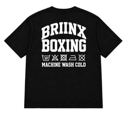 A black short-sleeve t-shirt shown from the back, featuring a bold white graphic print that reads 'BRIINX BOXING' with laundry care symbols and 'MACHINE WASH COLD' underneath, displayed on a neutral gray background.