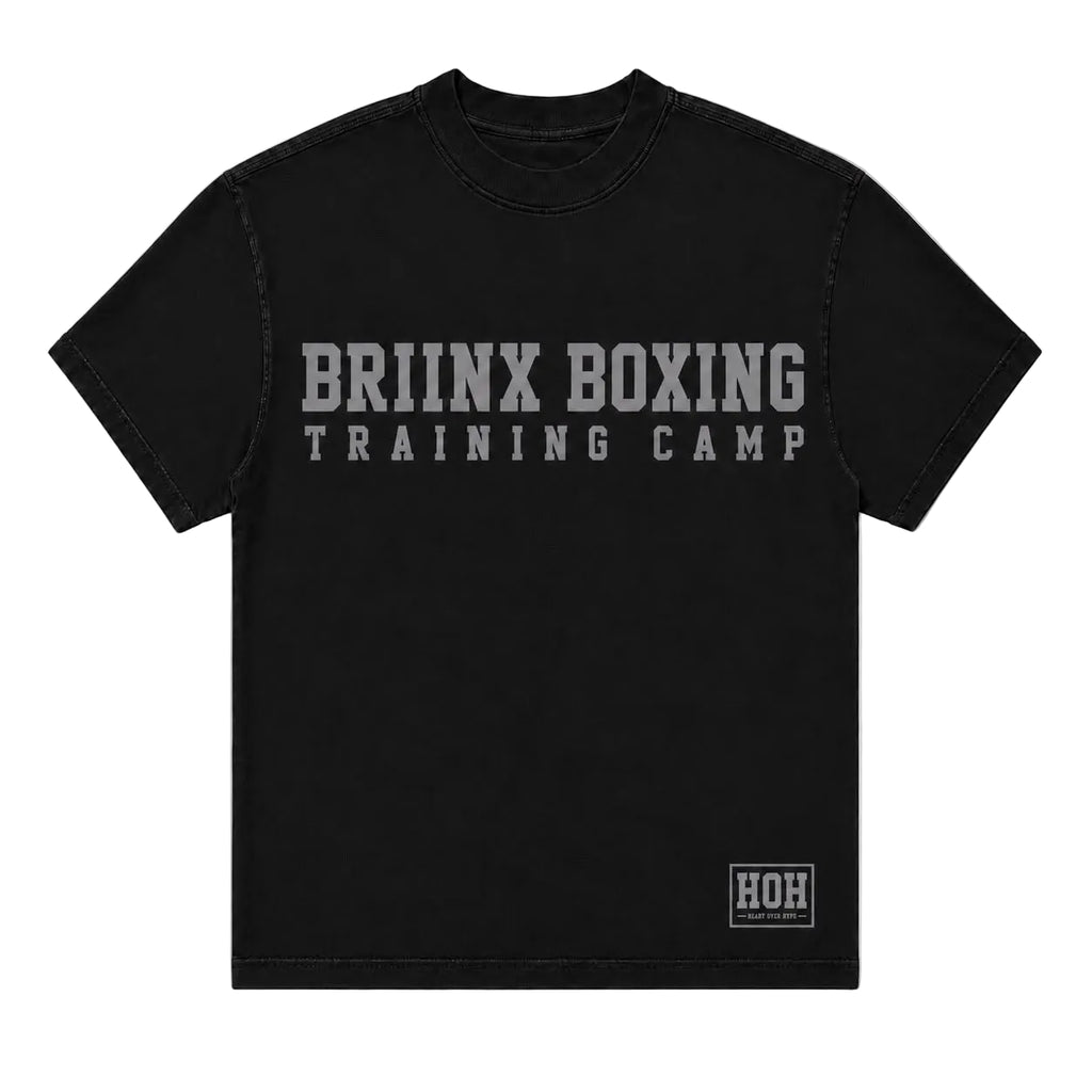 A black short-sleeve t-shirt with 'BRIINX BOXING TRAINING CAMP' printed in distressed gray letters across the chest, and a small 'HOH' logo patch on the bottom right hem, shown against a light gray background.