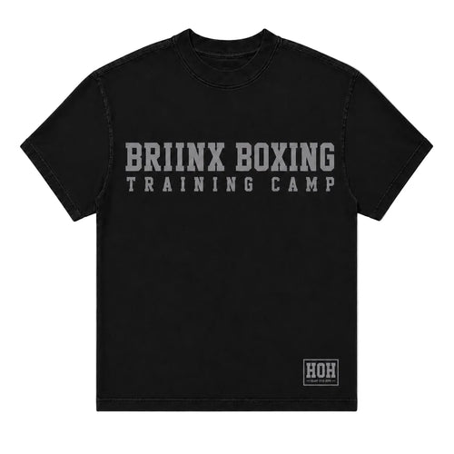 A black short-sleeve t-shirt with 'BRIINX BOXING TRAINING CAMP' printed in distressed gray letters across the chest, and a small 'HOH' logo patch on the bottom right hem, shown against a light gray background.